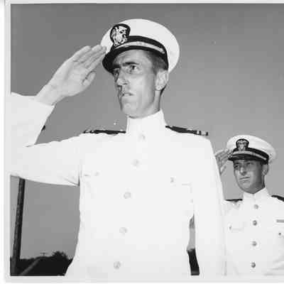 Two unidentified navy officers in dress uniforms saluting