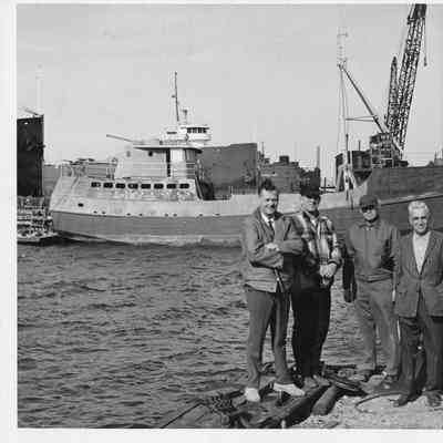 Group of men posing in front of vessel under construction at Sturgeon Bay Shipbuilding and Drydock Company November 3, 1965