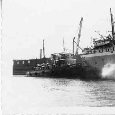 Tugboat John Roen IV next to stern of freighter
