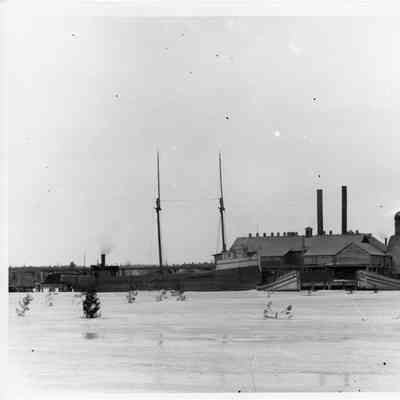 Vessels dockside in winter with buildings in background