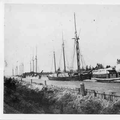Steam tug towing sailing vessels through canal