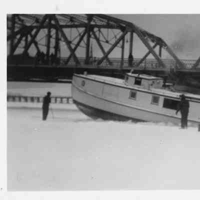Fishing tug breaking through ice in Bay of Sturgeon Bay with Michigan Street Bridge in background