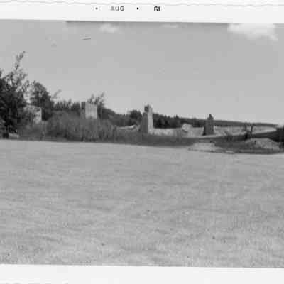Gravel lot with structures in background August 1961