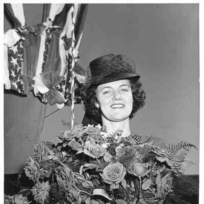 Woman holding flowers next to PC-1174 at ship christening