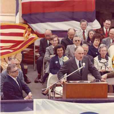 Man at podium with Ellsworth and Bob Peterson at launching of Discovery