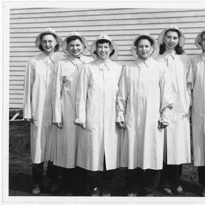 Six women in rain coats and caps