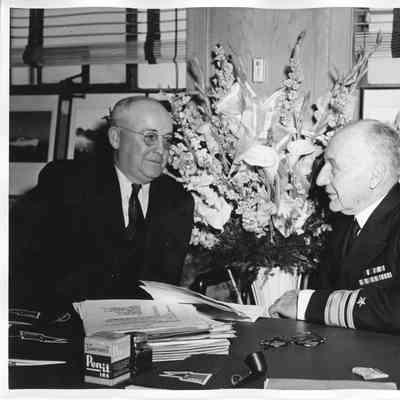 Sitting at desk L.D. Smith next to Rear Admiral William C. Watts