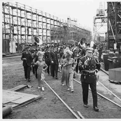 Uniformed marching band going through Leathem D. Smith Shipbuilding co. Yard