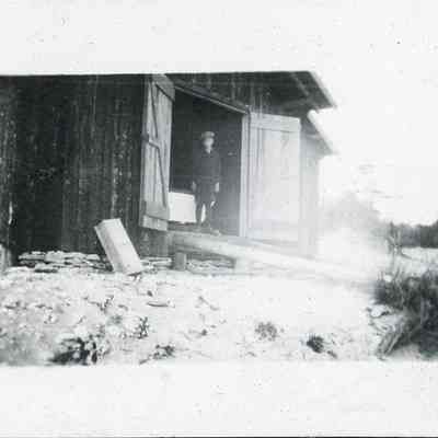 Boy stands in front of boathouse