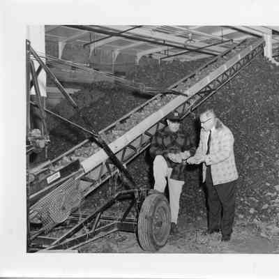 Potatoes in Conveyor belt with two men inspection some on Washington Island