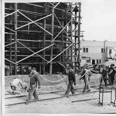 Men carrying line along railroad tracks