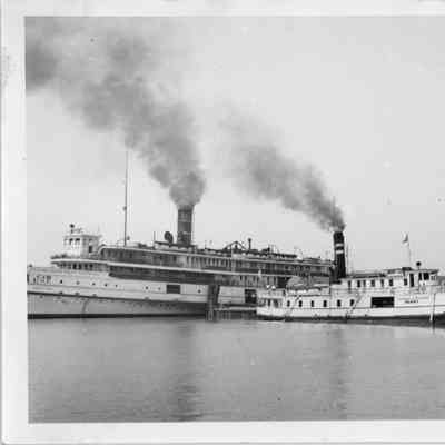 Ferry Erie Isle docked with steamship underway in background