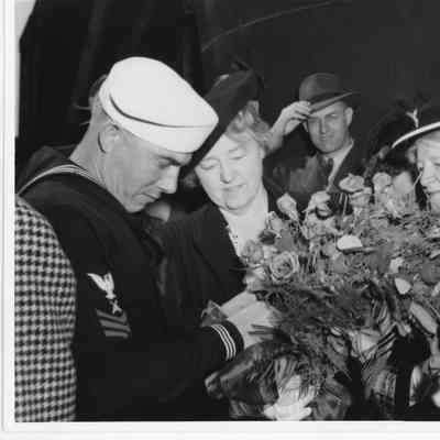 Mrs. William E. Wagener holding roses next to sailor at PC-1177 christening