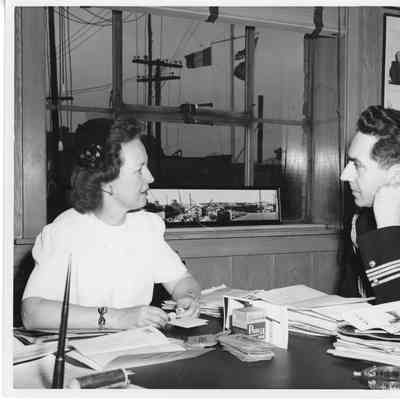 Alva Smith and man in uniform sitting at desk in office