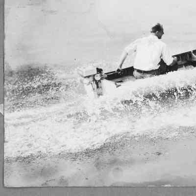 Two men on runabout underway with outboard motor running