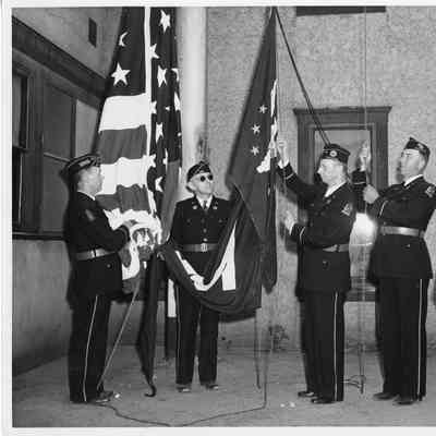 Five men in dark uniforms with American flag