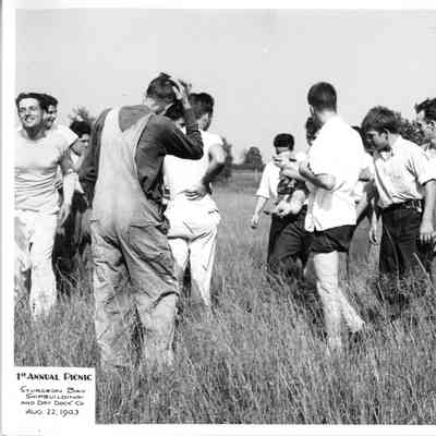 Group of men with one holding a pig at SBSB&DD Co. 1st annual picnic August 22, 1943