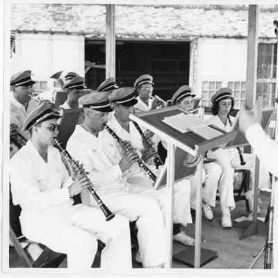 Band in white uniforms seated and playing