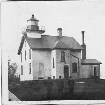 Pilot Island Lighthouse and outbuildings with three uniformed men standing outside