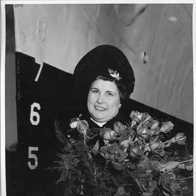 Mrs. C. Ray Christianson holding flowers in front of ship