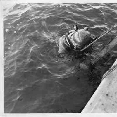Diver in suit standing on ladder in water