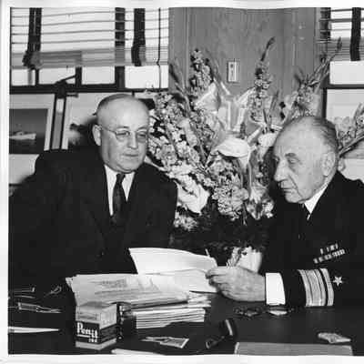 Sitting at desk L.D. Smith next to Rear Admiral William C. Watts