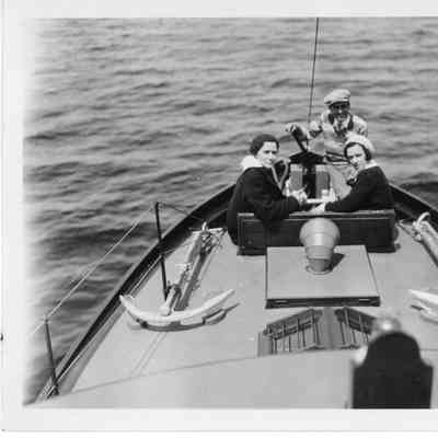 Two women and a man onboard a vessel looking at camera
