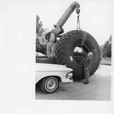 Two men standing next to Larc wheel being hoisted by a crane