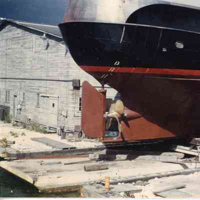 Silver, black, red strip and rust colored rear part of boat in cradle
