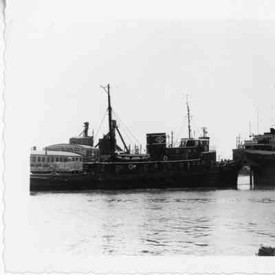 Tugboat John Roen IV at stern of freighter