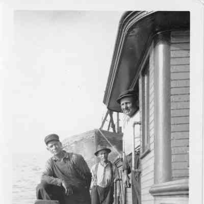 Three men on deck of vessel towing vessel