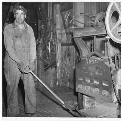 Man in overalls in workshop holding handle