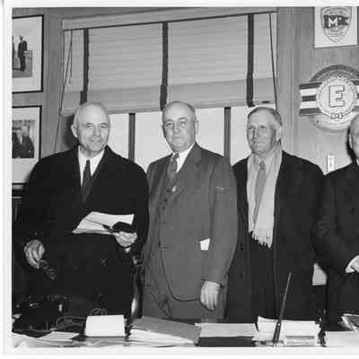 Leathem D. Smith and three men standing in office