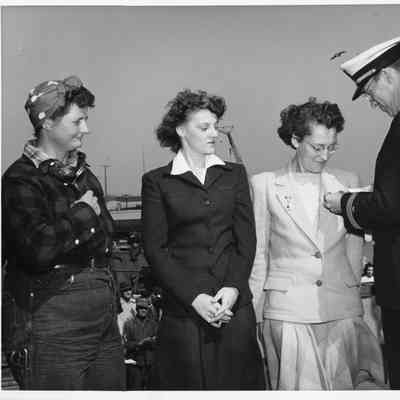 Navy man pinning awards on three L.D. Smith female employees