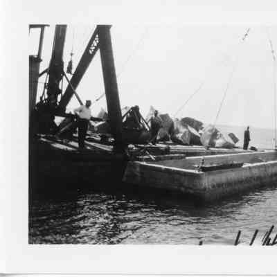 Men standing on crane platform next to rocks