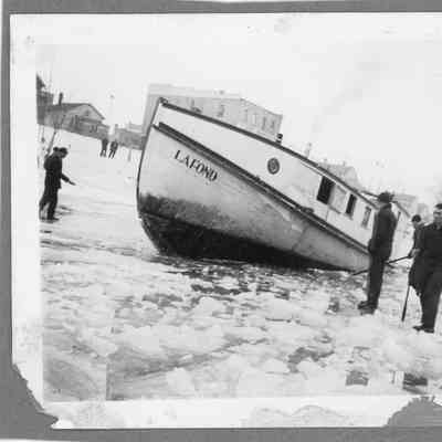 Fishing tug Lafond stuck in ice with people walking around it