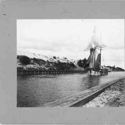 Man standing on a schooner carrying lumber through canal