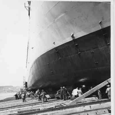 Hull on skids with workmen nearby at Leathem D. Smith Shipbuilding
