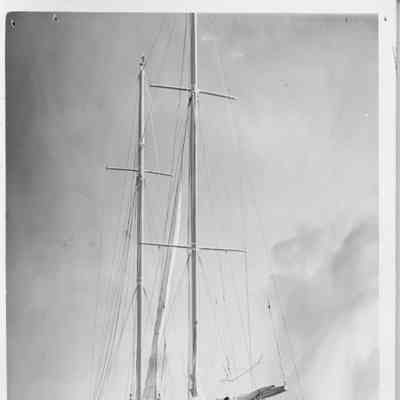 Sailboat moving by motor with men on deck