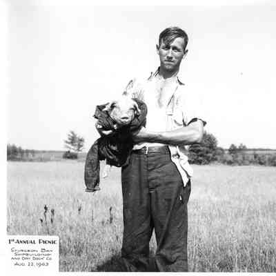Man holding pig at SBSB&DD Co. 1st annual picnic August 22, 1943