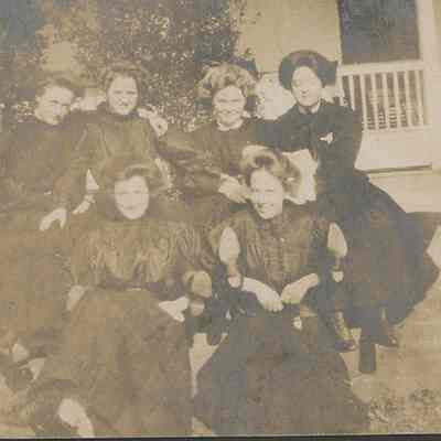Six young women sitting on porch