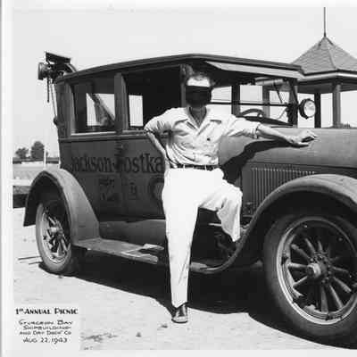 Man posing with car at SBSB&DD Co. 1st annual picnic August 22, 1943