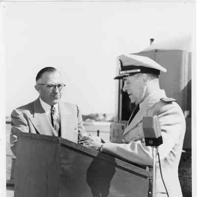 C. Ray Christianson and Captain Jack Roe standing with microphone