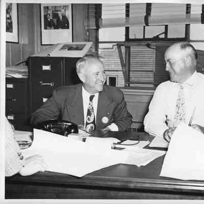 Unidentified man with L.D. smith sitting at desk