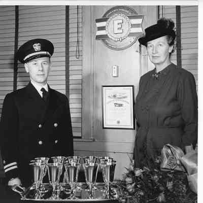 Woman and serviceman in Leathem D. Smith Office behind 12 glasses on silver platter