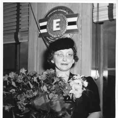 Mrs. John Butterweck holding bouquet of roses in Leathem D. Smith Office