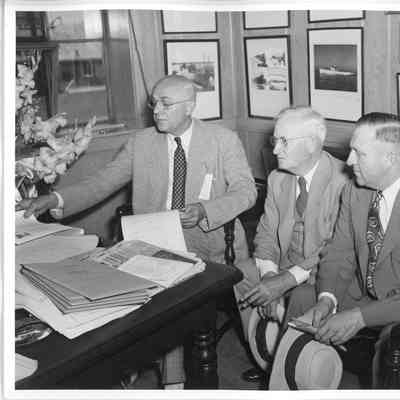 two unidentified men and C. Ray Christianson in office