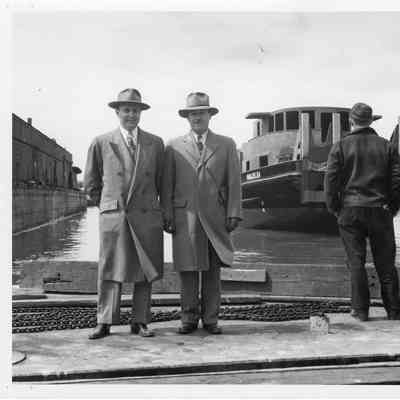 2 men in suits with the Marjelea in background