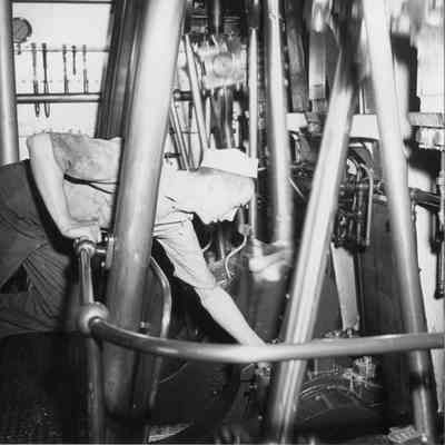 Sailor working on engine of lighthouse tender Hollyhock