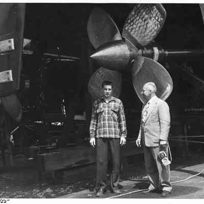 Fred Peterson with man and 4-blade propeller at Peterson Boat Works April 23, 1955